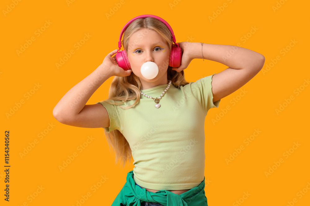 Cute trendy girl in headphones blowing bubble gum on yellow background Cute trendy girl in headphones blowing bubble gum on yellow background