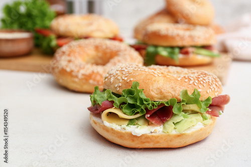 Tasty bagel sandwich with prosciutto and avocado on white background