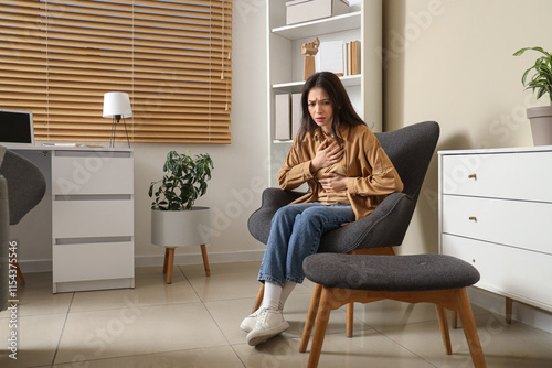 Portrait of worried young woman sitting in armchair at home