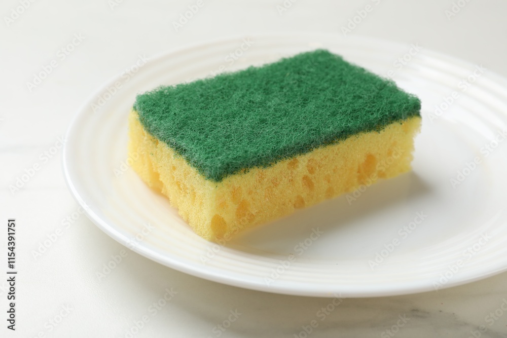 Soft sponge and plate on white table, closeup