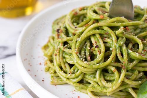 Green spaghetti with spinach pasta sauce in a dish with fork. Close-up. Selective focus. Eating healthy homemade vegan comfort food.