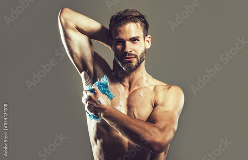 Skincare and body care. Muscular man taking refreshing shower washing his body with soap foam. Handsome guy cleaning body with foamy gel using washcloth, enjoying morning hygienic routine in bathroom.