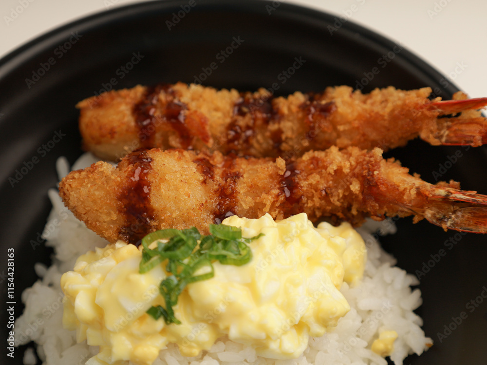rice with fried shrimp and teriyaki sauce served with egg mayonnaise in black bowl rice with fried shrimp and teriyaki sauce served with egg mayonnaise in black bowl