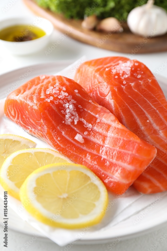 Pieces of fresh salmon with salt and lemon on white table, closeup Pieces of fresh salmon with salt and lemon on white table, closeup