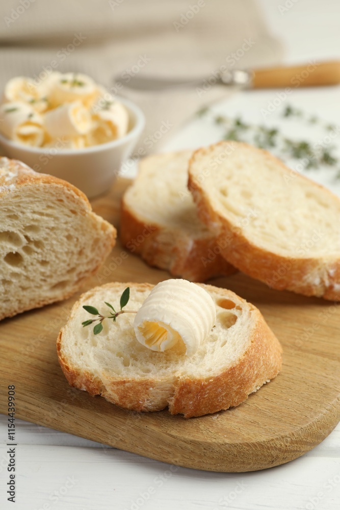 Cut baguette with butter and herbs on white wooden table, closeup Cut baguette with butter and herbs on white wooden table, closeup