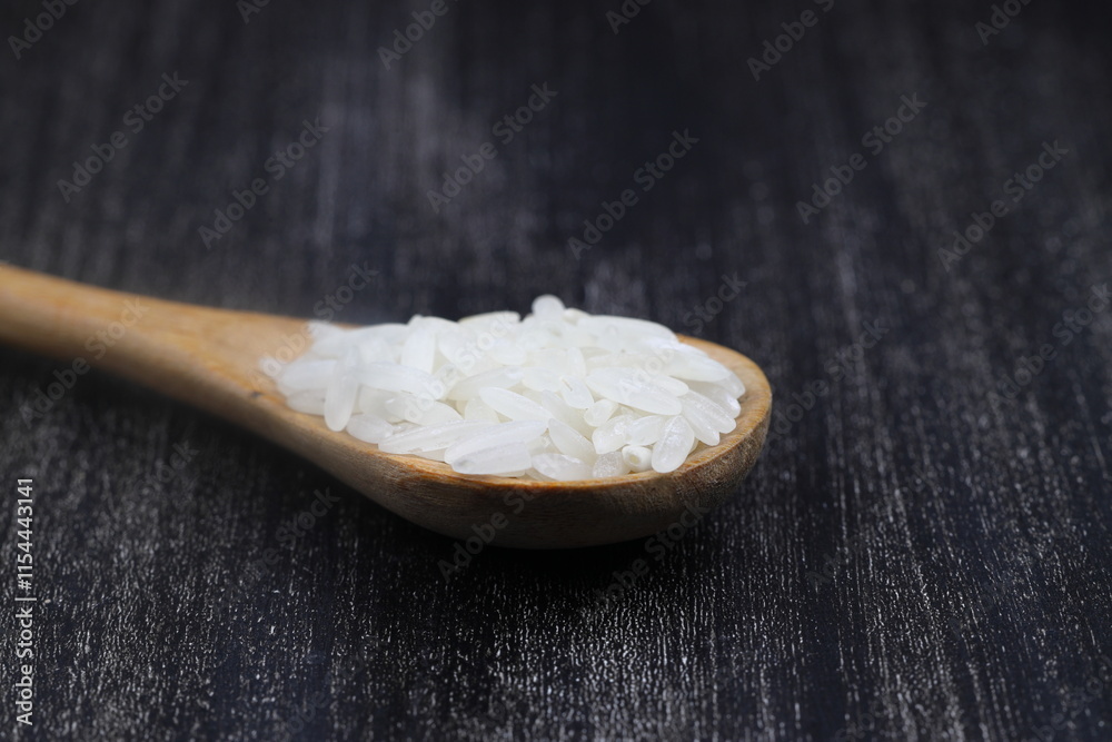 Raw white rice on wooden background. Long uncooked rice in wooden plate. Natural organic food. Traditional Asian cereal culture. Raw white rice on wooden background. Long uncooked rice in wooden plate. Natural organic food. Traditional Asian cereal culture.
