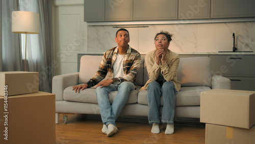 Upset African American married couple sad family renters home owners sit on sofa cuddling worried moving out apartment frustrated woman and man relocation bank debt credit mortgage eviction sale house