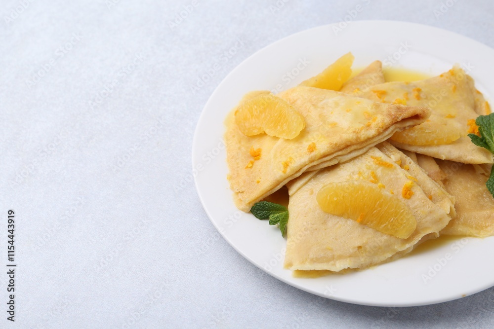 Plate with tasty crepes Suzette on light textured table, closeup. Space for text Plate with tasty crepes Suzette on light textured table, closeup. Space for text