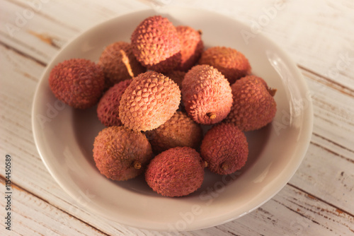 Ripe lychee fruits (Litchi chinensis) on a white plate photo