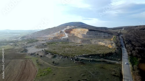 A large cement mine site and old mining areas that have been rehabilitated with pine trees. Slow motion with aerial video