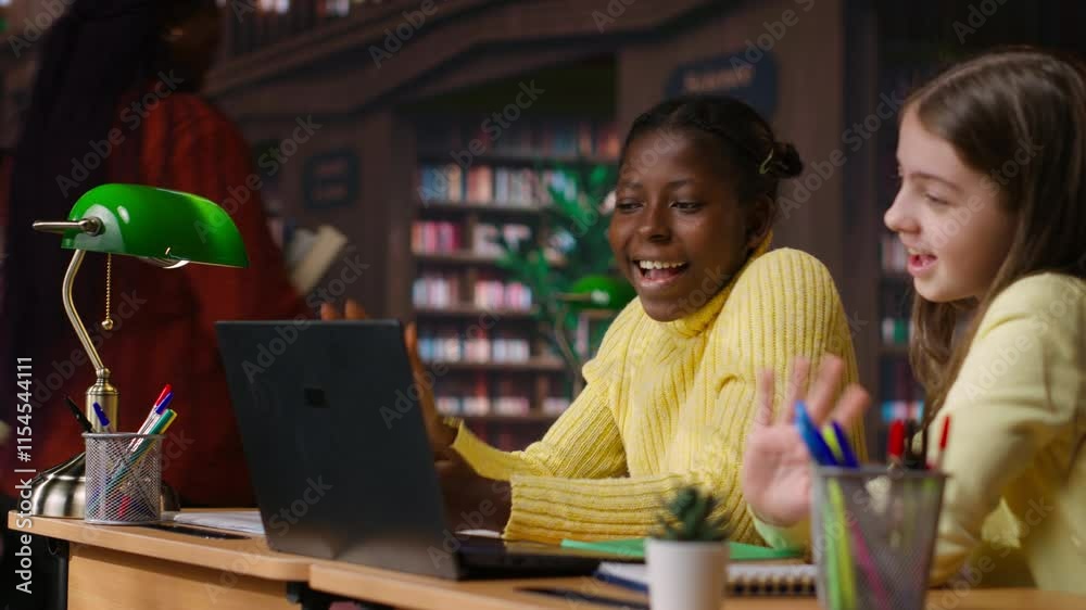 Primary school pupils in a library discuss during an online seminar, using tech to connect with educator and classmates for an interactive virtual chat. Remote lesson via web conference. Camera B.
