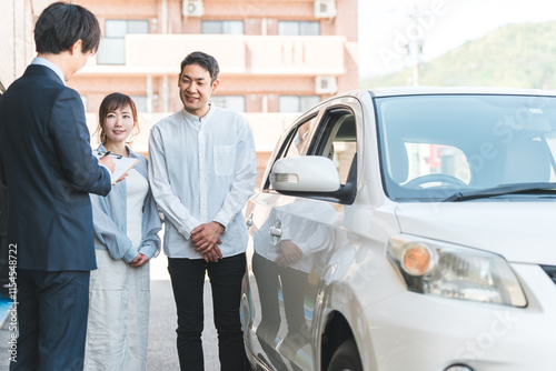 自動車購入・査定・買取にきた夫婦と接客するセールスマンの若いアジア人男性
 photo