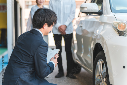 Fototapeta 自動車購入・査定・買取にきた夫婦を接客するセールスマンの若いアジア人男性 