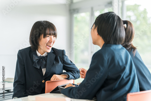 学校で授業中に後ろの席の生徒と話す小学生・中学生・高校生・女子高生（友達）
 photo