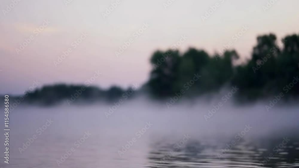 A close-up of mist rising from the surface of a calm lake in the early morning, with trees on the horizon. A close-up of mist rising from the surface of a calm lake in the early morning, with trees on the horizon.