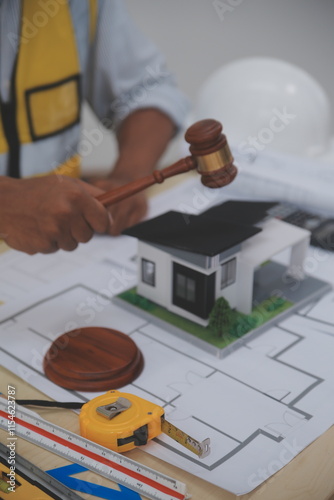 Judge gavel on building blueprint plans with a yellow safety helmet in the background. law that deals with matters relating to building construction, engineering. Construction law concept. photo