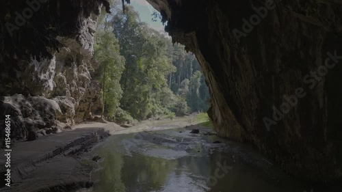 This stunning drone footage captures the serene beauty of Nam Lod Cave in Mae Hong Son, North Thailand. The light illuminates the cave entrance revealing a stream flowing through the rock formations.