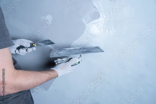 A person applies microcement to a wall surface with a putty knife in a workshop.