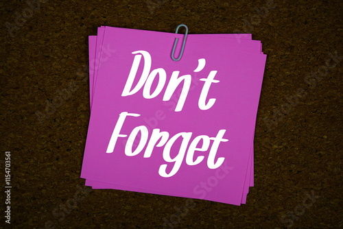 Don't Forget text on sticky note on cork board background