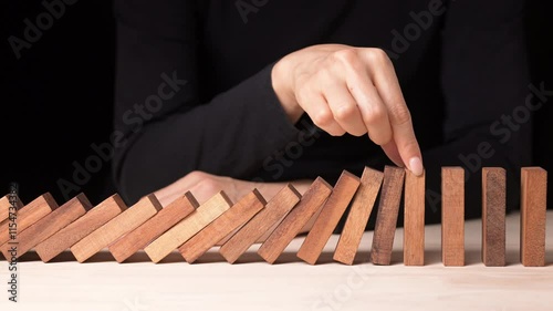 Risk Management Strategies Hand Stopping Falling Dominos in a Business Crisis - Decision Making Concept in Slow Motion