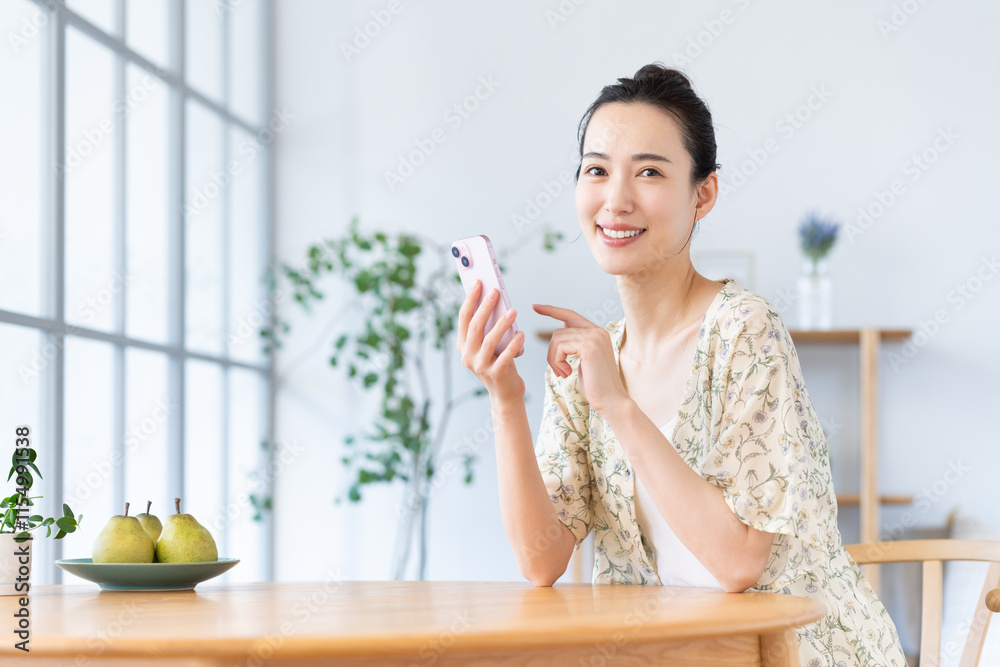 家でスマホを使う若い女性