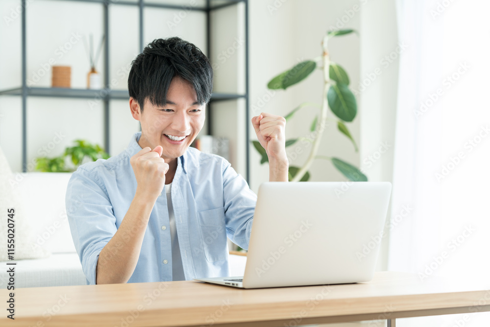 リビングでパソコンを使う若い男性 リビングでパソコンを使う若い男性