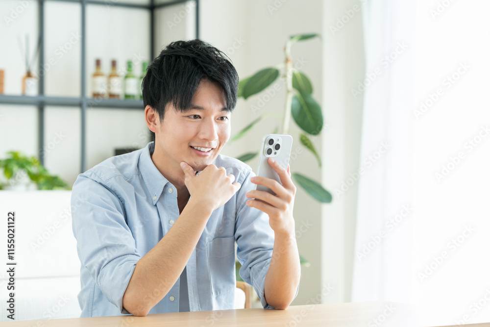 リビングでスマホを見る若い男性 リビングでスマホを見る若い男性