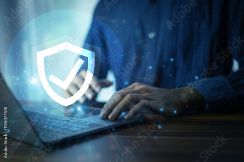 Man working on a laptop with advanced cyber security shield, ensuring the protection of sensitive data and securing the digital environment against potential threats.
