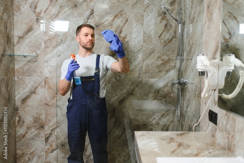 Cleaning service concept. Man cleaning glass cabinet in bathroom photo