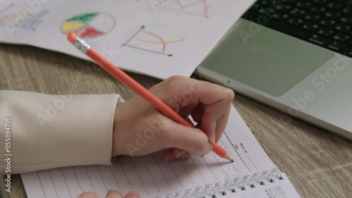 Businesswoman jotting down notes in diary at desk in office 