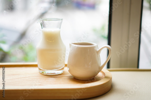 A glass jar of milk and a cup of espresso on a wooden tray with selective focused.