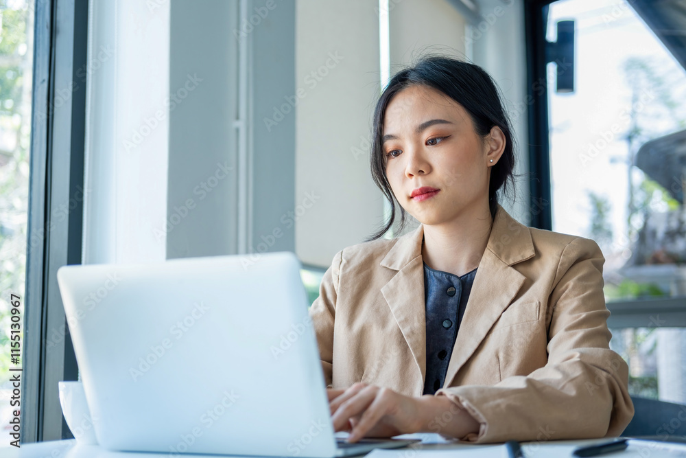 Businesswoman sitting at desk on couch in workplace or at home working on laptop and analyzing data on charts and graphs and writing on papers to make business plan and strategies for company, startup Businesswoman sitting at desk on couch in workplace or at home working on laptop and analyzing data on charts and graphs and writing on papers to make business plan and strategies for company, startup