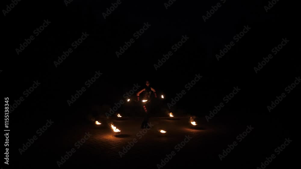 A stuntwoman performing at night with burning torches. A professional fire show. A young woman is dancing with a burning rod. In the foreground are the props for a fiery performance. A stuntwoman performing at night with burning torches. A professional fire show. A young woman is dancing with a burning rod. In the foreground are the props for a fiery performance.