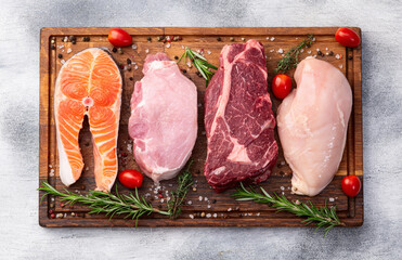 Mix of raw meat and fish . Salmon , beef , pork , chicken staek . Top view
