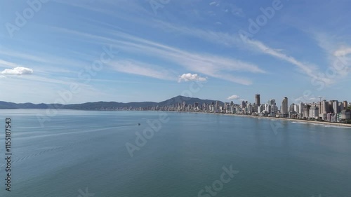 Flying over blue sea of Meia Praia coast with skyscrapers in background. Itapema, Brazil photo