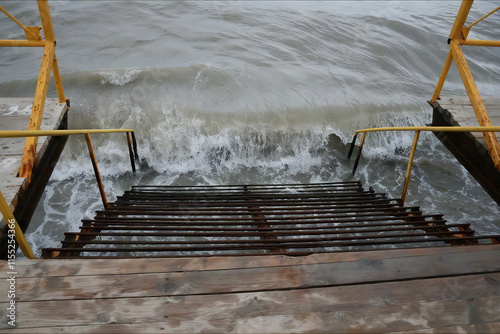 Old iron ladder in the sea against the backdrop of the surf