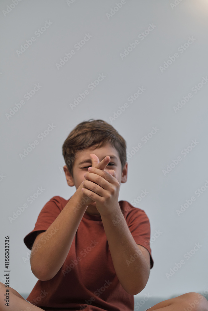 A playful boy sitting cross-legged on a sofa, pretending to aim with his hands. His joyful demeanor brings a lively and carefree atmosphere to the moment. A playful boy sitting cross-legged on a sofa, pretending to aim with his hands. His joyful demeanor brings a lively and carefree atmosphere to the moment.