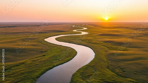 Winding river at sunset in vast grasslands landscape with golden horizon