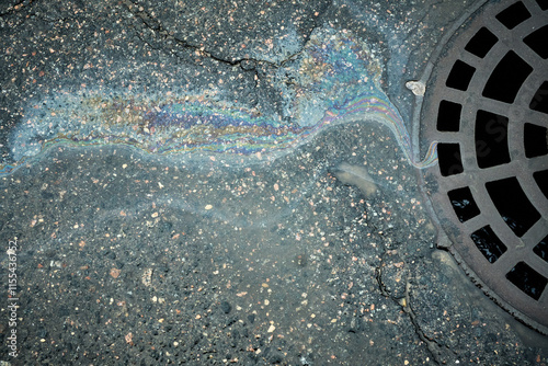 фотографія Iridescent gasoline polluting street flowing towards storm drain, environmental