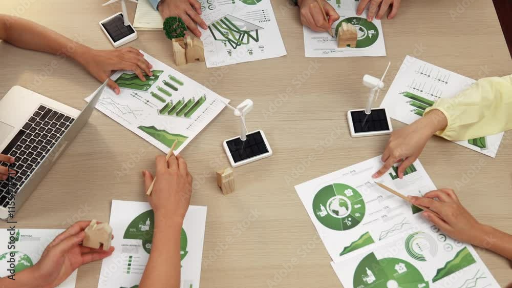 Excellent business team discussing on eco house project at meeting table with windmill design model and green power usage graph for decreasing carbon footprint, save earth. Focus on hand. Delineation. Excellent business team discussing on eco house project at meeting table with windmill design model and green power usage graph for decreasing carbon footprint, save earth. Focus on hand. Delineation.