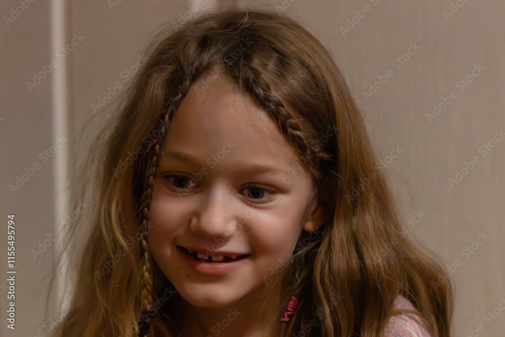 A cheerful young girl with long, wavy hair and braided details smiles brightly indoors, capturing a candid, joyful moment. Background softly blurred. A cheerful young girl with long, wavy hair and braided details smiles brightly indoors, capturing a candid, joyful moment. Background softly blurred.