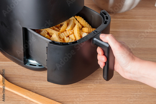 Woman at home using trendy kitchen gadget air fryer machine cooking deep-fried potato, small countertop convection oven, deep fast frying oil free, more healthful way to cook deep-fried food photo