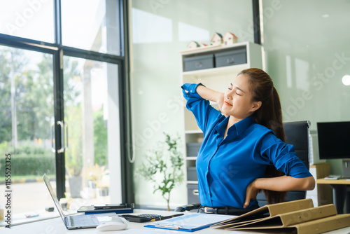 A businesswoman working at a desk in an office struggles with stress and headaches caused by Office Syndrome, a condition linked to prolonged sitting excessive computer use during long working hours