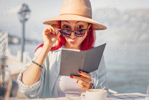 Shocked Woman Reacting to High Prices at a Seaside Cafe or Restaurant photo