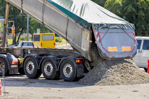 Obraz na płótnie Heavy truck unloads gravel at busy construction site in bright daylight w salonie