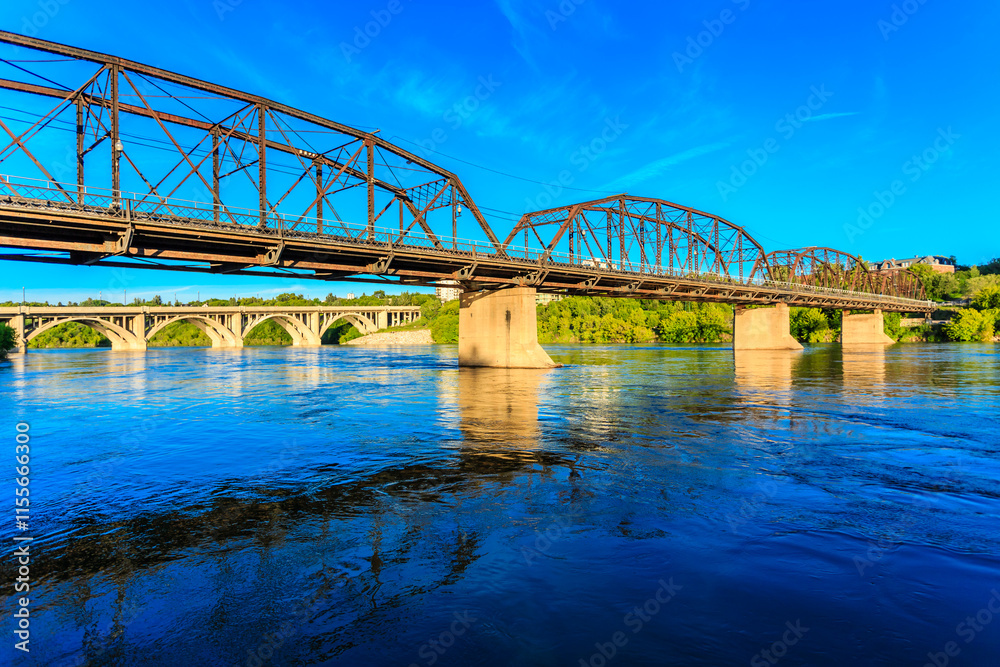 Fototapeta premium A bridge spans a river with a blue sky in the background