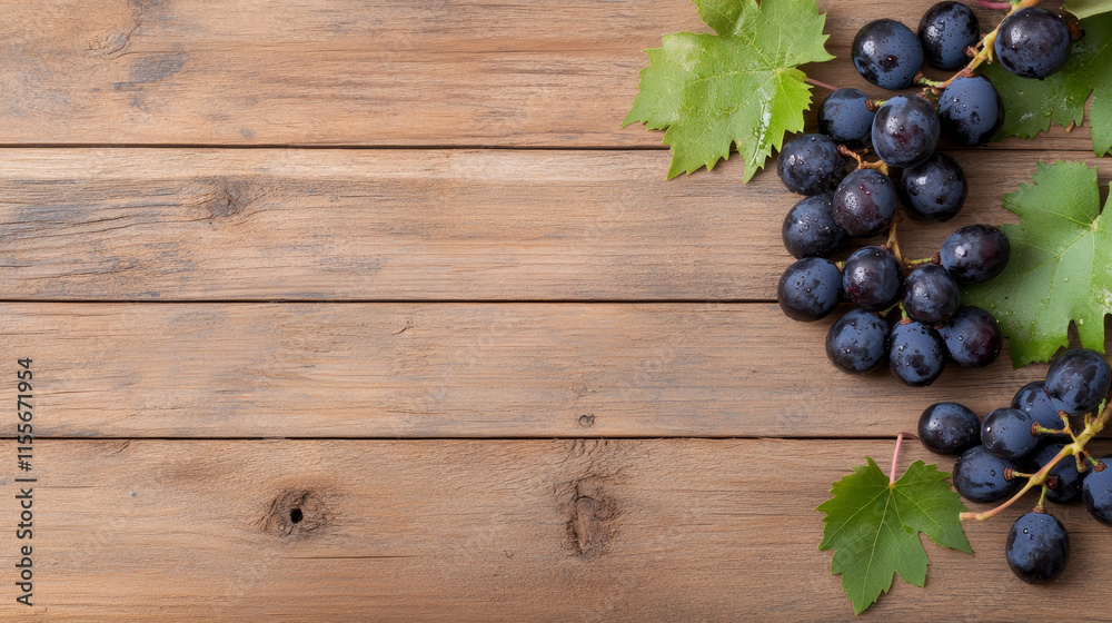 Fototapeta premium Fresh black grapes with green leaves on a rustic wooden background in natural light