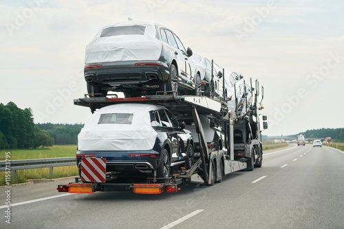 SUVs being delivered on two-level trailer truck photo