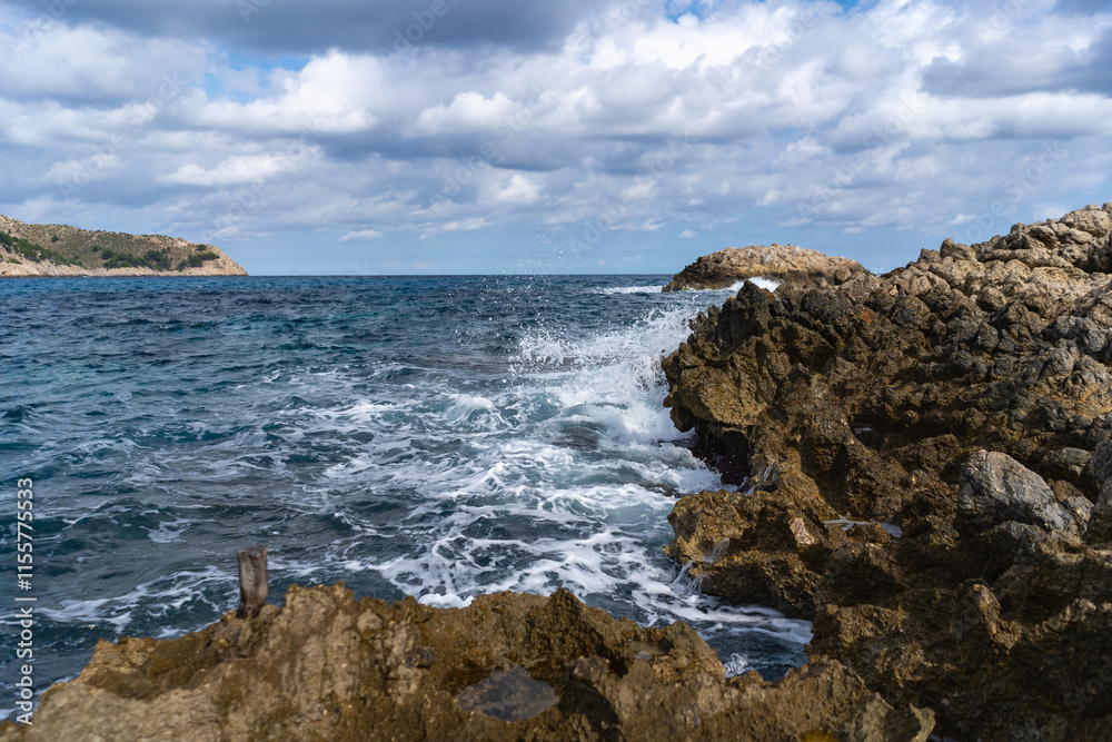 Cala Agulla, Mallorca, Spain, October 27, 2021 - Dramatic waves crashing against rocky coastline with Mediterranean blue waters Cala Agulla, Mallorca, Spain, October 27, 2021 - Dramatic waves crashing against rocky coastline with Mediterranean blue waters