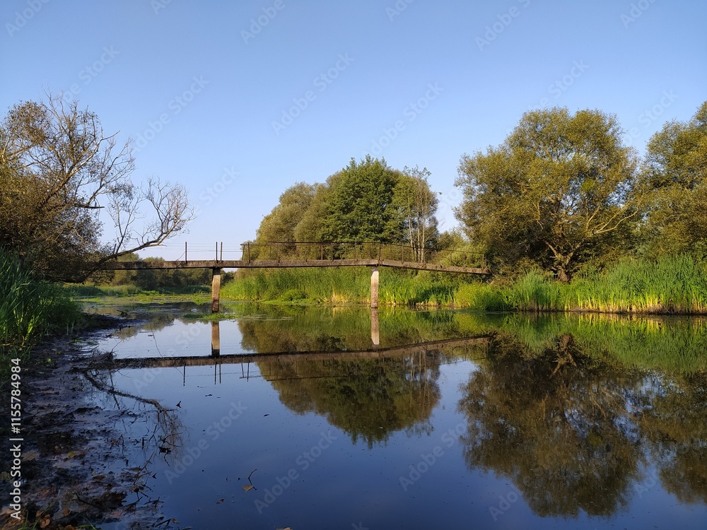 Fototapeta premium Bridge over the river with reflection in the water on a sunny day